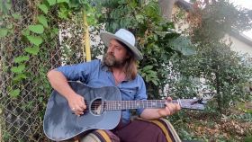 Holmes at his house in scene::St. Pete, playing his Thompson Guitar.